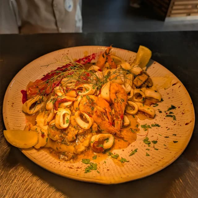 Staff iiin striped shirts serving inside a food truck.